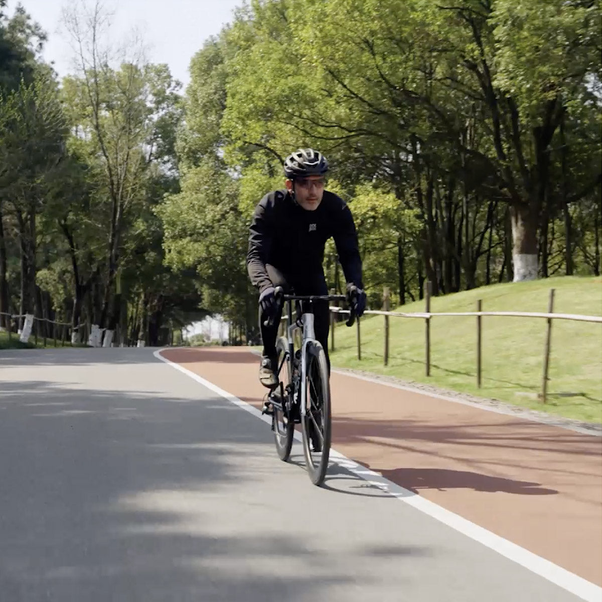 Radfahrer auf dem Radweg in Parklandschaft, trägt ROCKBROS selbsttönende Sportbrille.