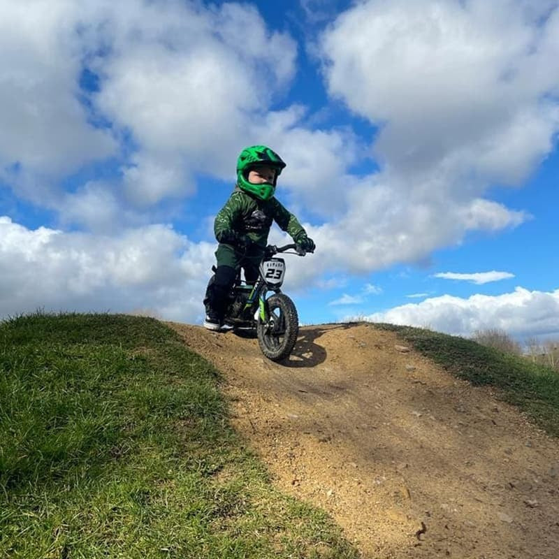 Kind mit ROCKBROS Fullface-Kinderhelm fährt über Dirt-Hügel im Gelände – Schutz beim Offroadfahren.